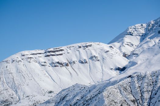 Captivating view of snow-covered mountains under a clear blue sky, showcasing nature's winter beauty.