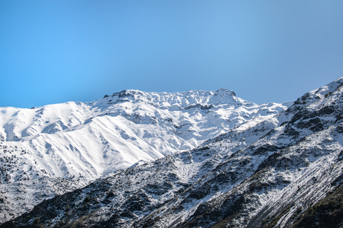 Free Stunning winter scene of a snow-covered mountain range under a clear blue sky. Stock Photo