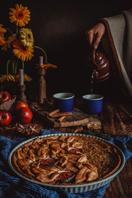 Free Warm apple pie with tea being poured, surrounded by autumn decor and apples. Stock Photo