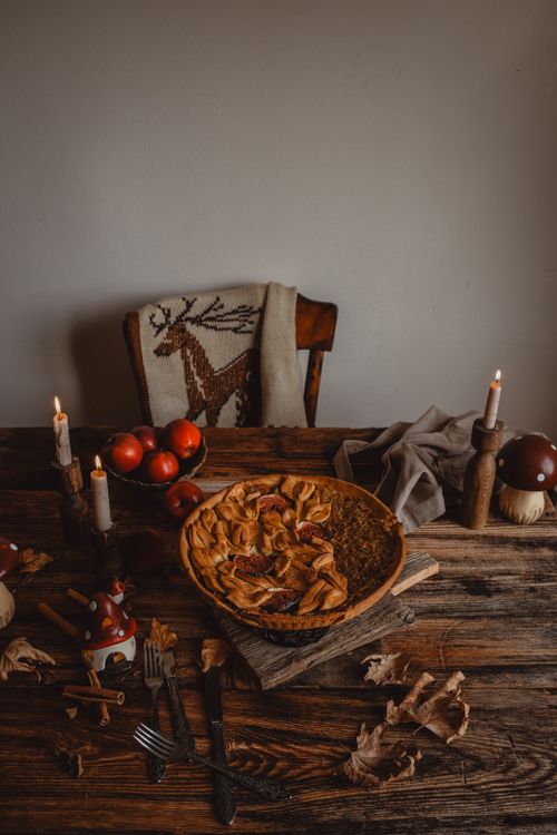 Free A rustic apple pie surrounded by candles and apples on a wooden table creates a cozy fall atmosphere. Stock Photo