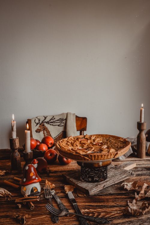 Free Warm apple pie with rustic decor and candles, perfect for a cozy setting. Stock Photo