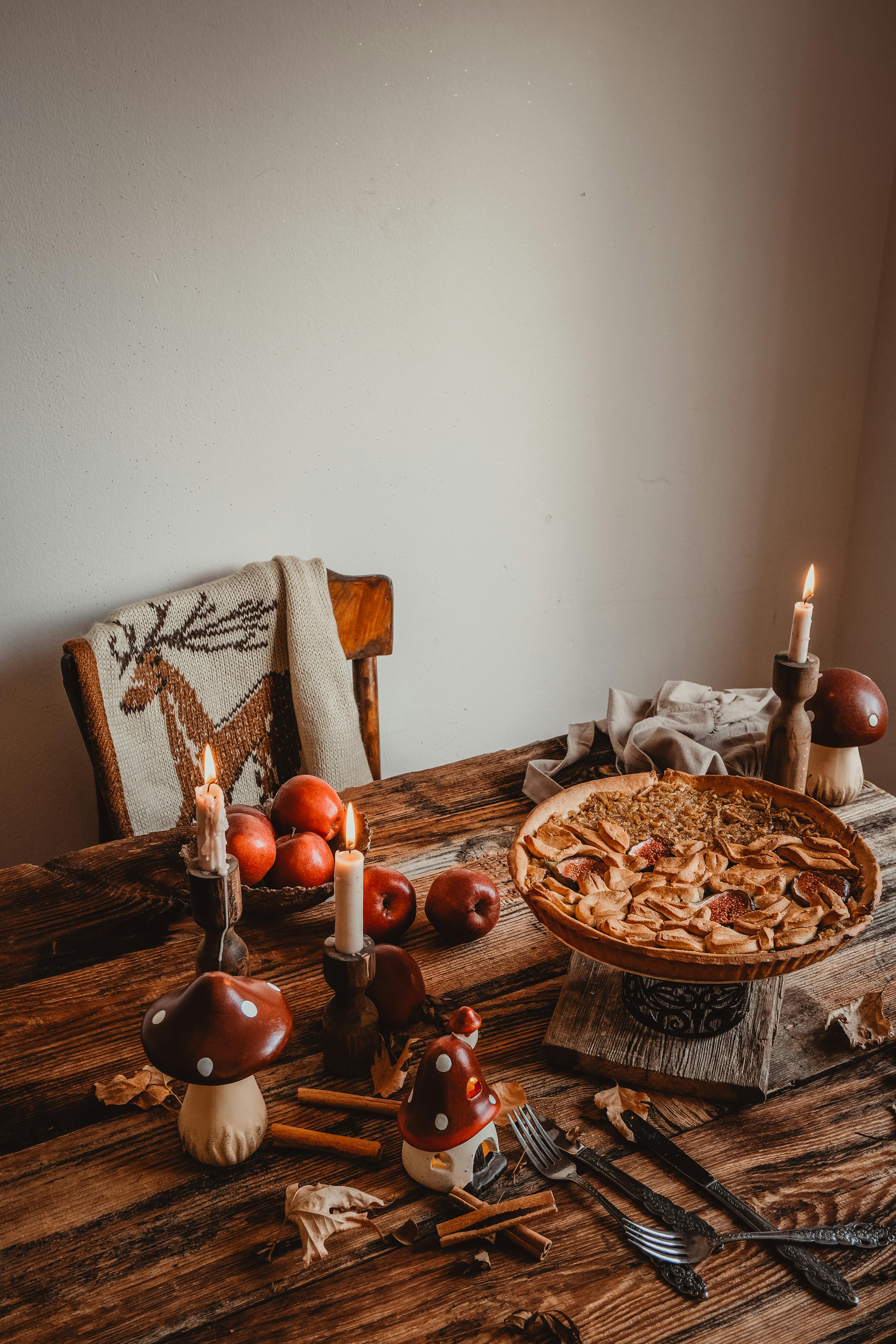 Warm rustic autumn table with apple pie, candles, and cozy decor.