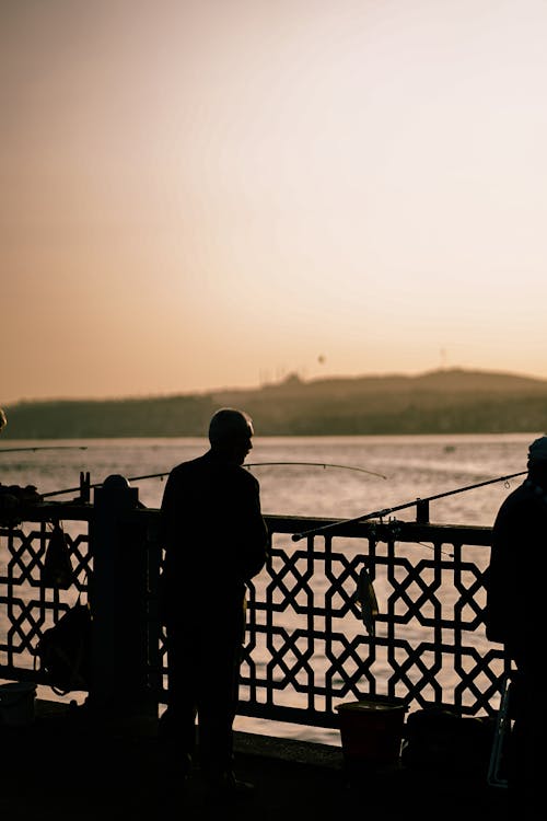 Silhouettes of Fishermen on a Bridge 
