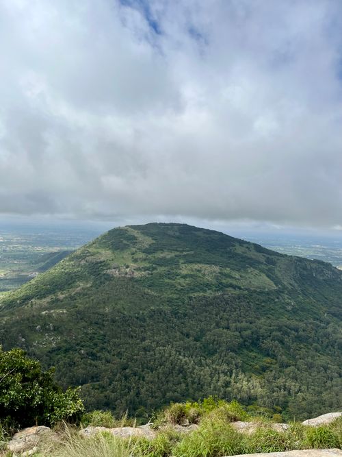 Free A picturesque view of a green mountain enveloped by a cloudy sky, epitomizing natural beauty. Stock Photo