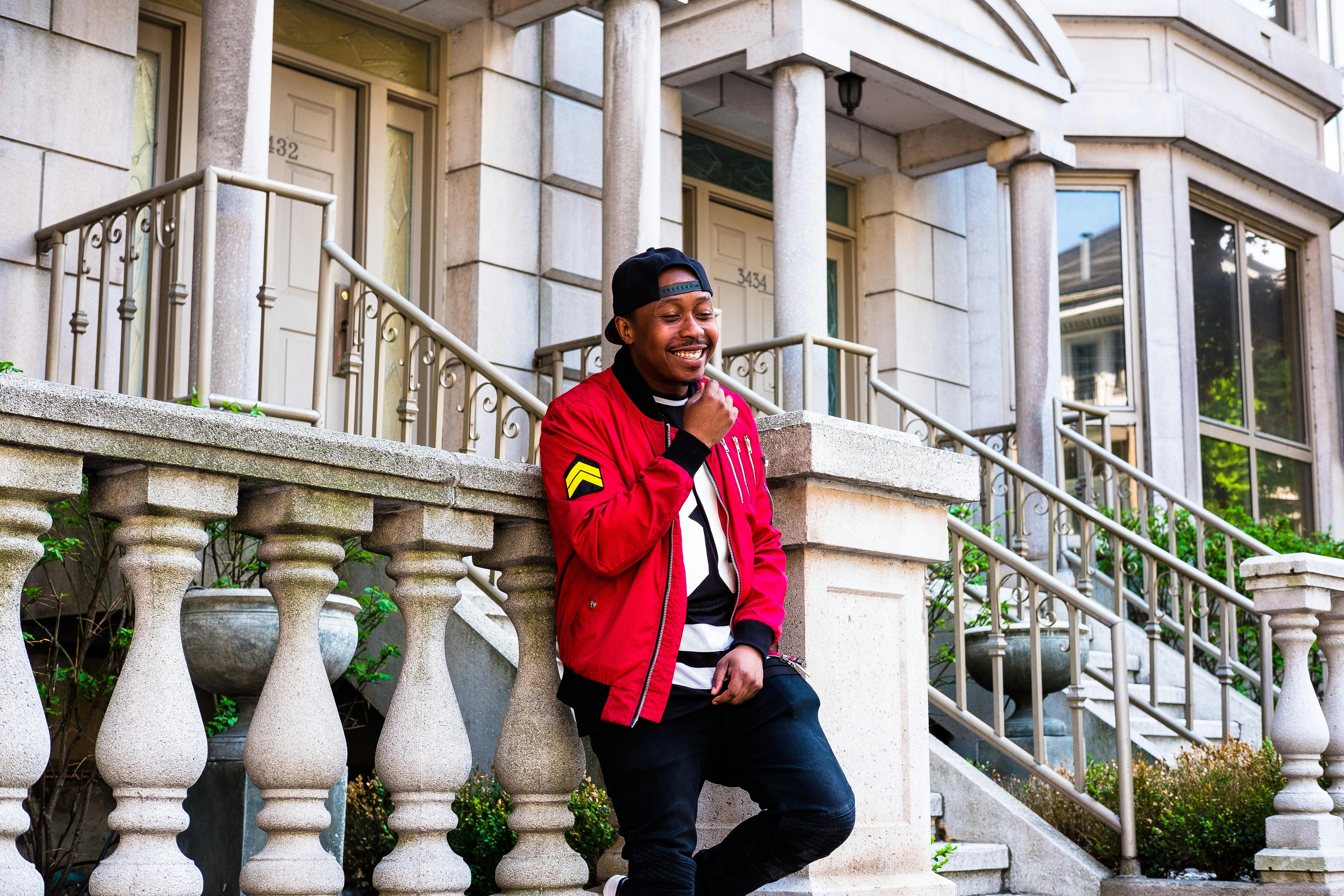 一个开朗的男人穿着休闲街头服饰，在时尚的门廊上摆姿势