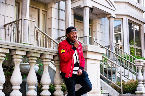 Photo of Smiling Man Leaning on Gray Stone Railing