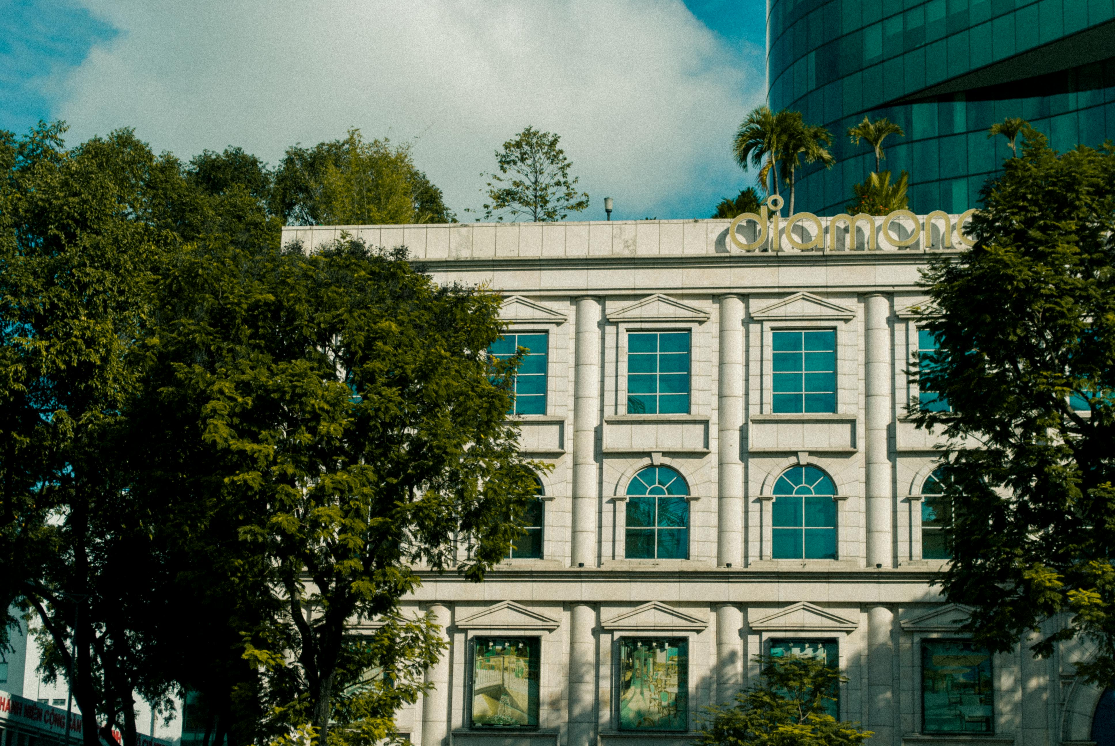 Free Ornate white building facade with trees and windows in Ho Chi Minh City, Vietnam. Stock Photo