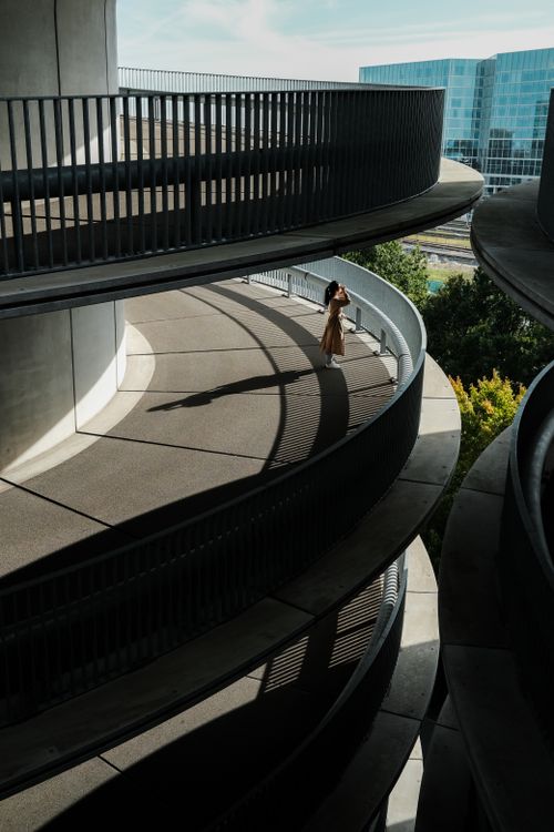 Free Woman stands on spiral ramp in urban setting, casting a shadow. Stock Photo