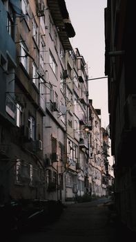 Dusk view of a narrow alley in an urban area with high-rise residential buildings.