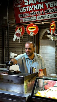 A street vendor grilling kofte at a market stall, featuring a lively night scene with street food preparation.