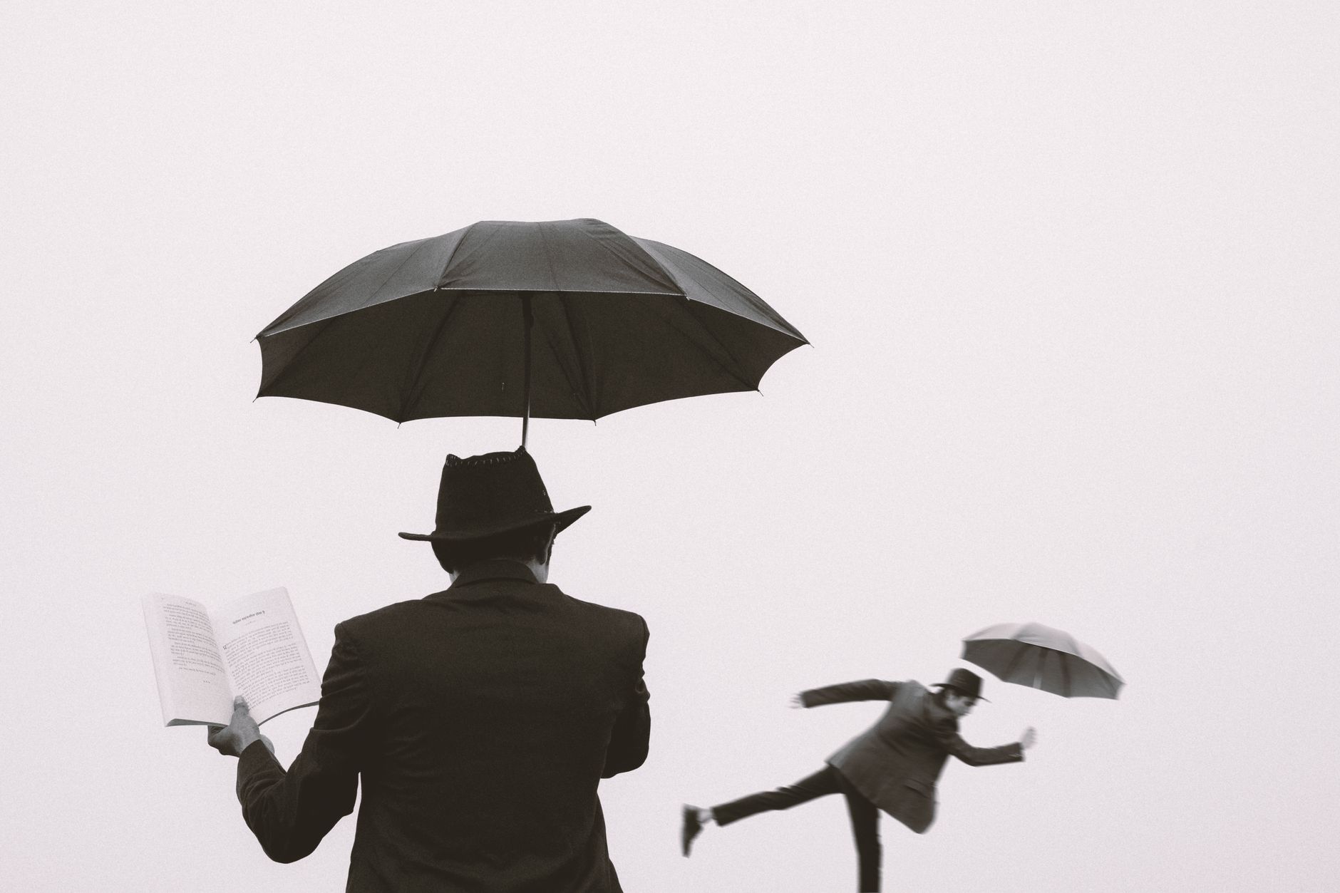 Conceptual black and white photo of men with umbrellas, creating a surreal atmosphere.