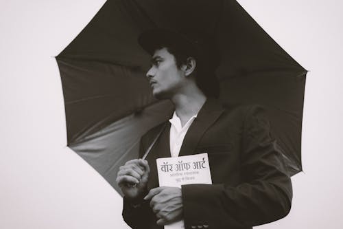 Fine-Looking Man in Suit with Umbrella Holding Book