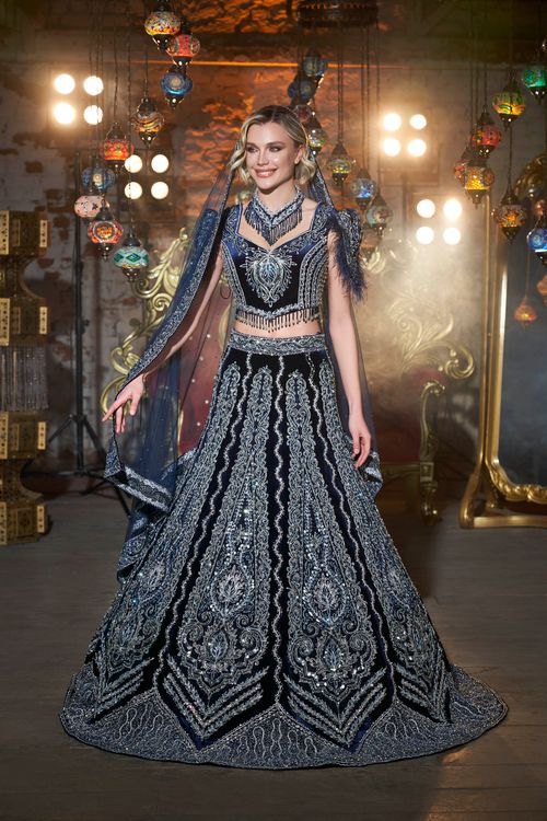Free A woman in a beautifully ornamented traditional dress stands gracefully indoors with decorative lights. Stock Photo