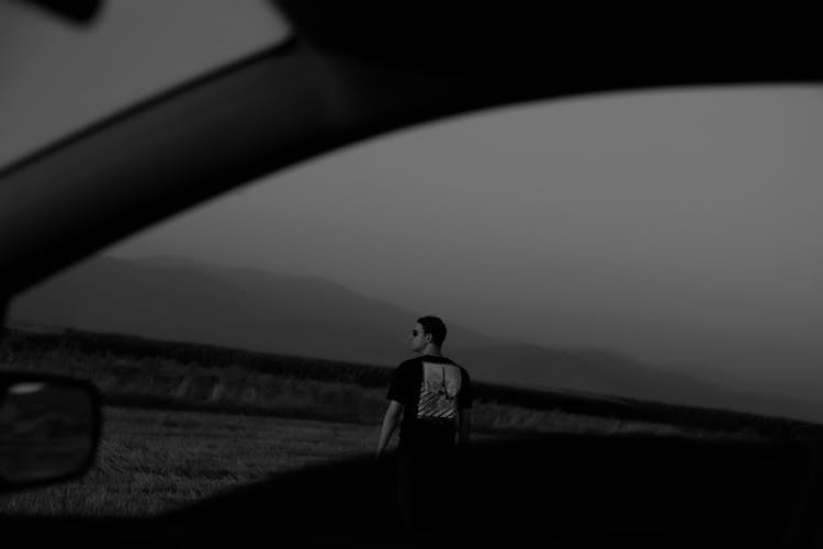 Man Standing Behind Car Window In Black And White