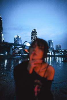 Artistic urban night scene with blurred woman and city skyline reflections.