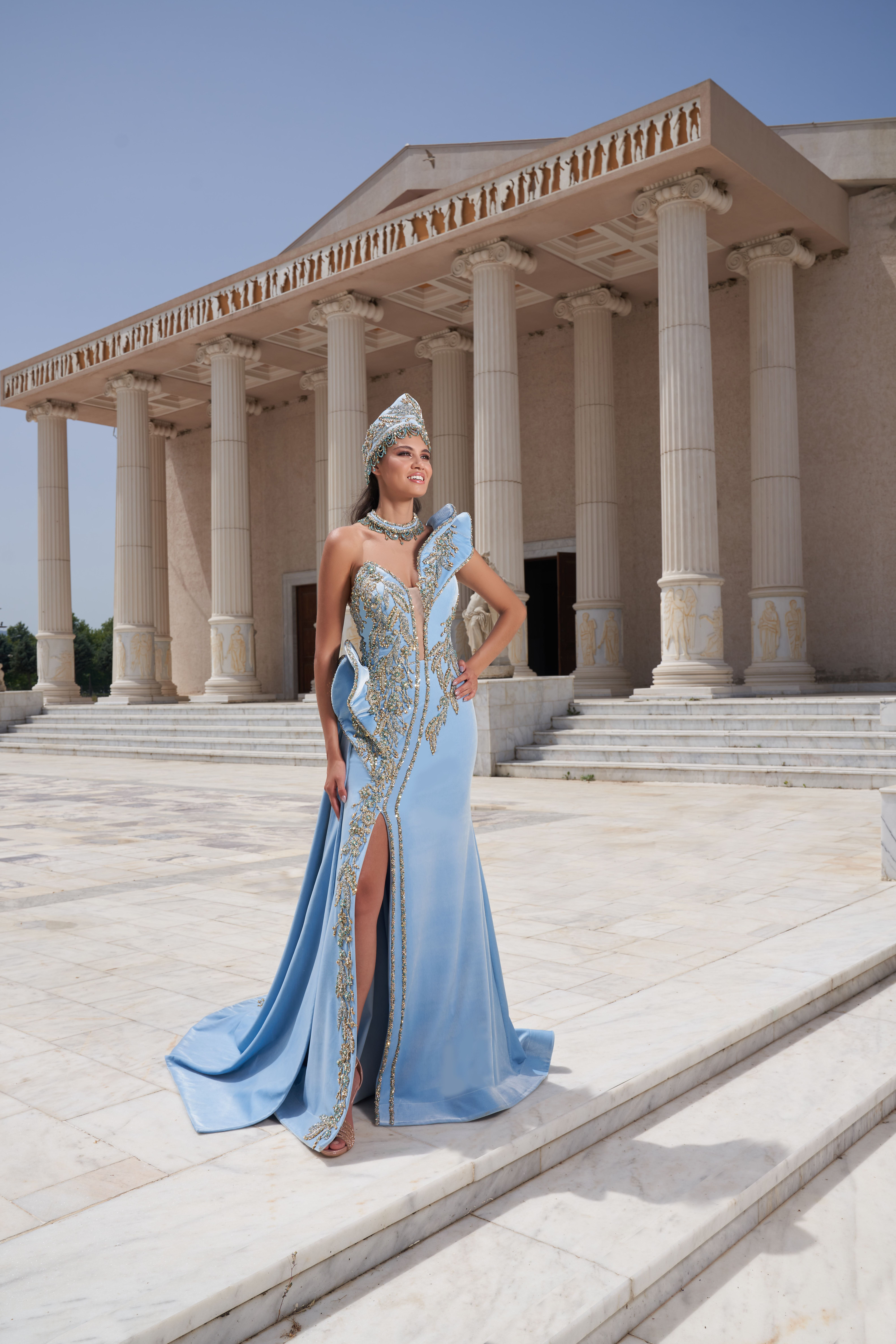A stylish woman poses in a blue gown at a historic temple in Izmir, Turkey.