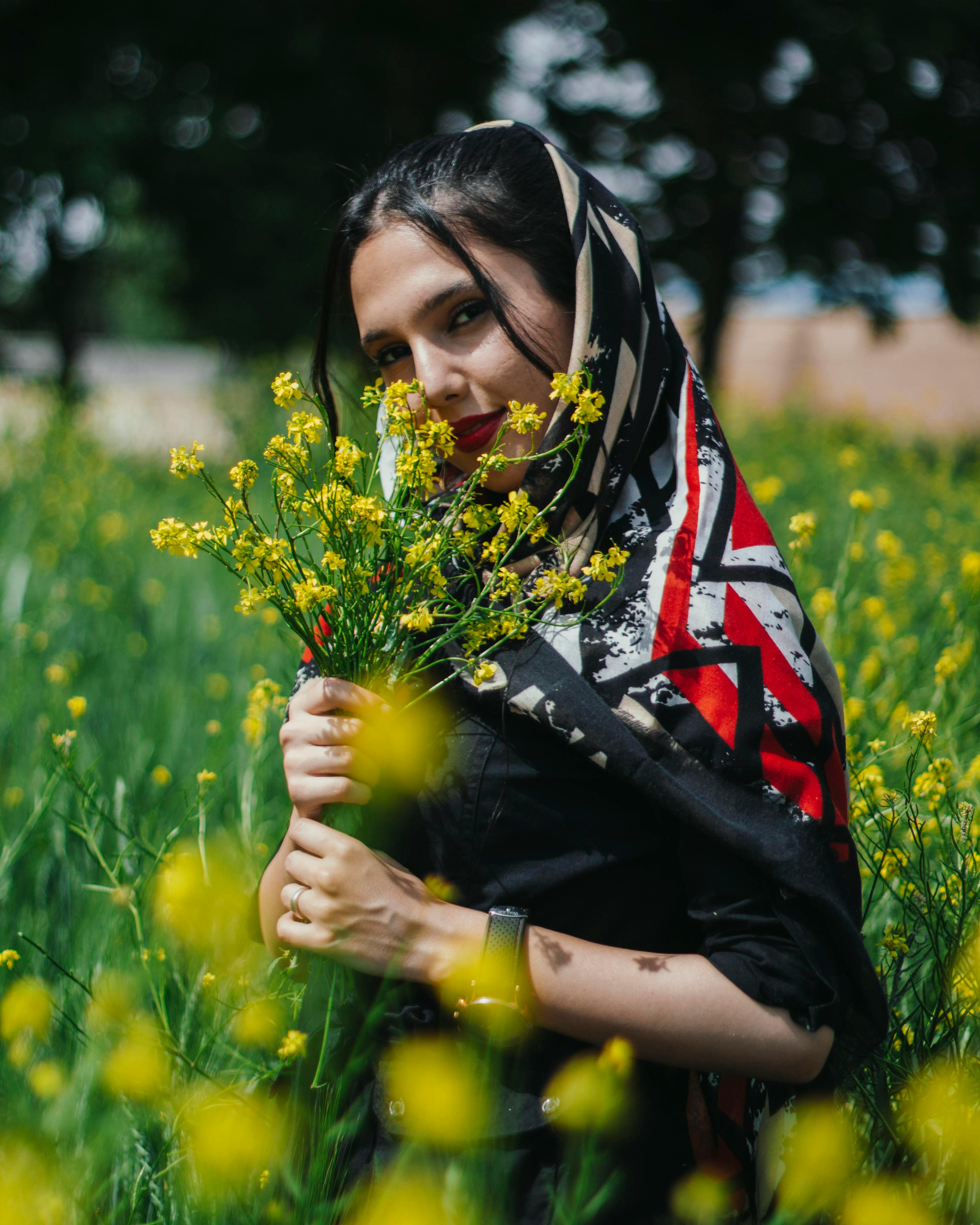 pretty woman with yellow flowers in hands posing on meadow