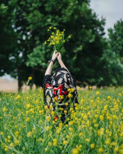 Woman with Headscarf Holding Yellow Flowers in Air