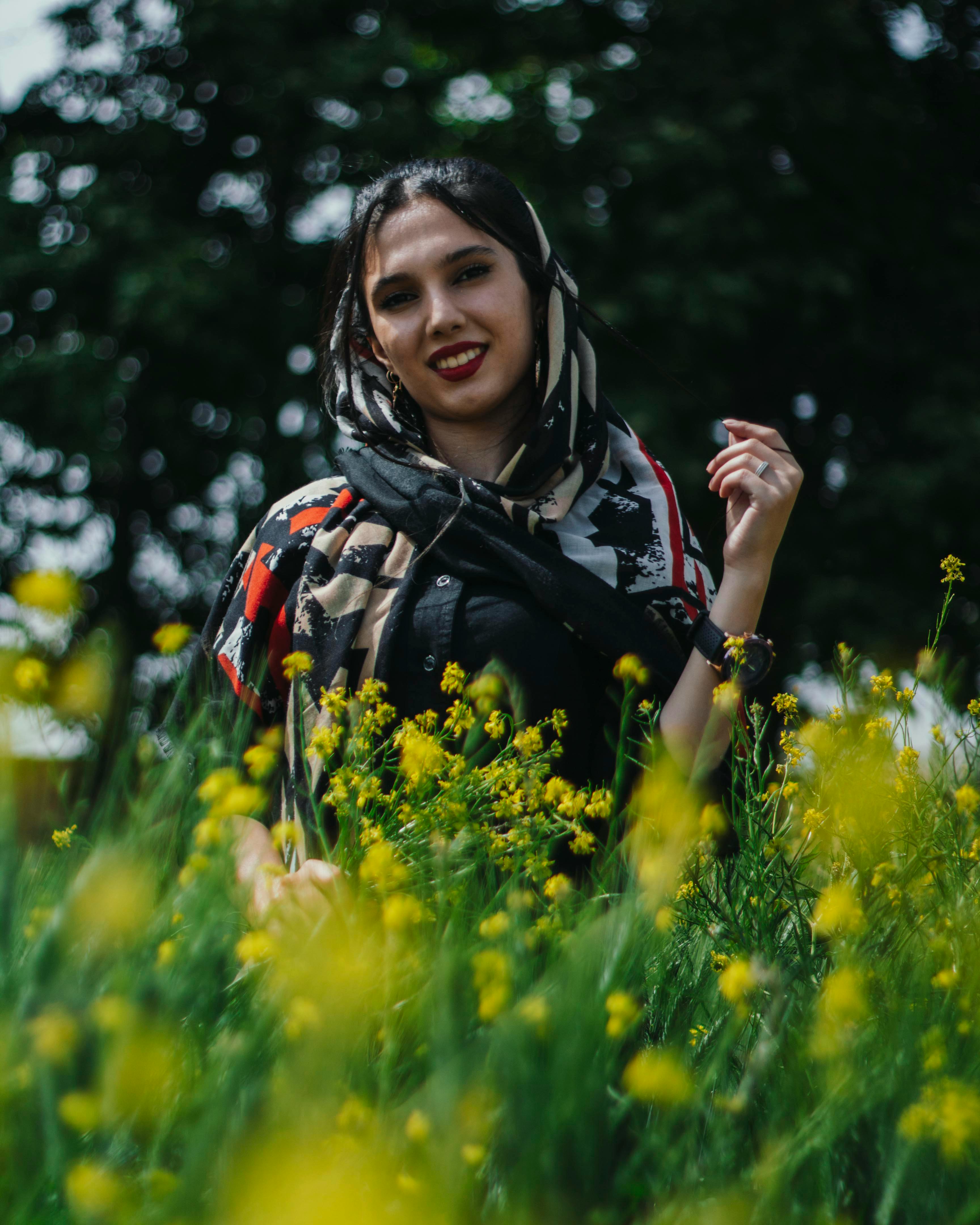 smiling woman in dress posing among yellow flowers