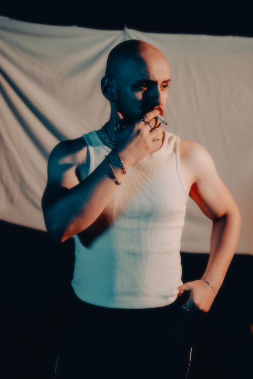 Free A dramatic nighttime portrait of a bald man smoking, wearing a tank top. Stock Photo