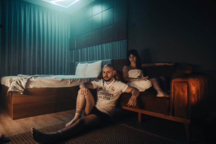 Man And Woman Sitting On Couch And Floor In Room