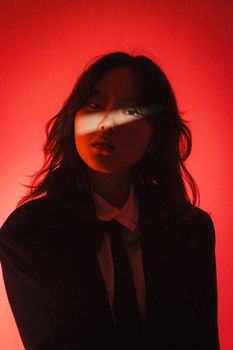 Striking portrait of a woman in dynamic lighting with a vivid red background.