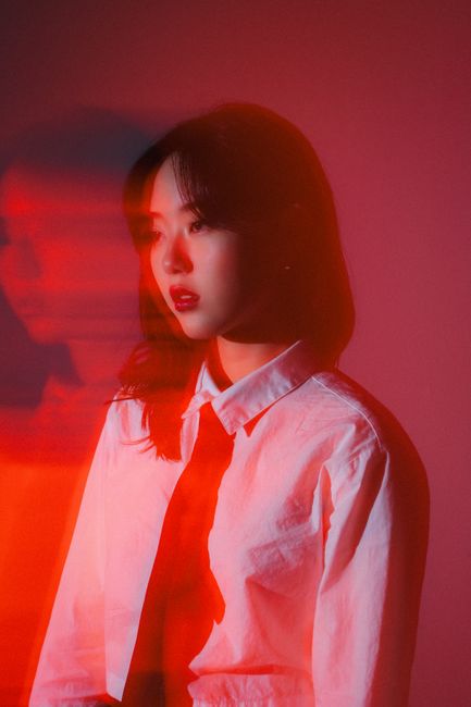 Creative fashion portrait of an Asian woman with dramatic red lighting and blurred effect.