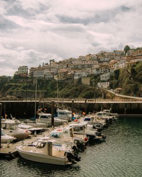 Picturesque view of Lastres marina in Spain, nestled against hillside buildings under a bright sky.