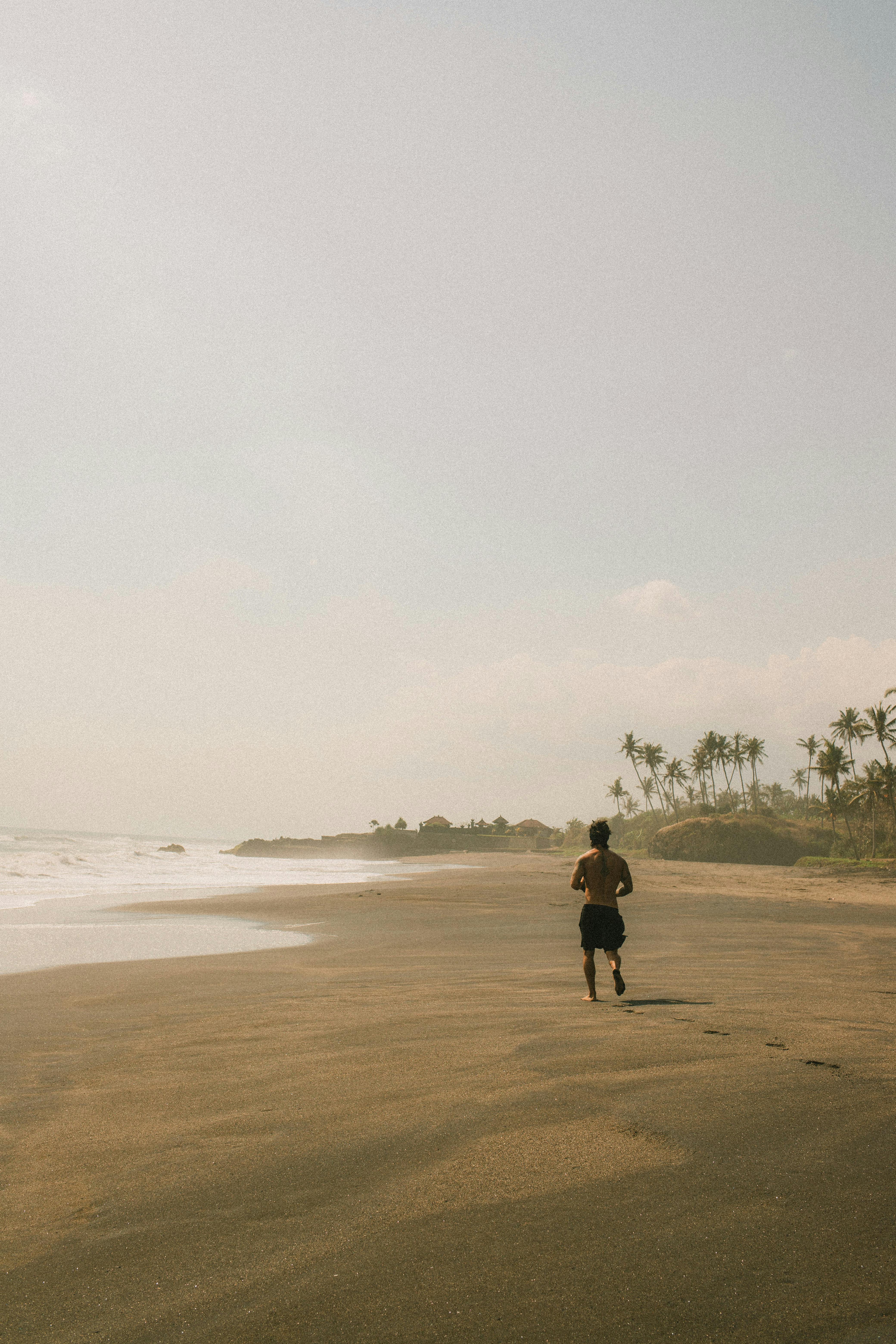 A man running along a quiet tropical beach, creating a serene and active atmosphere.