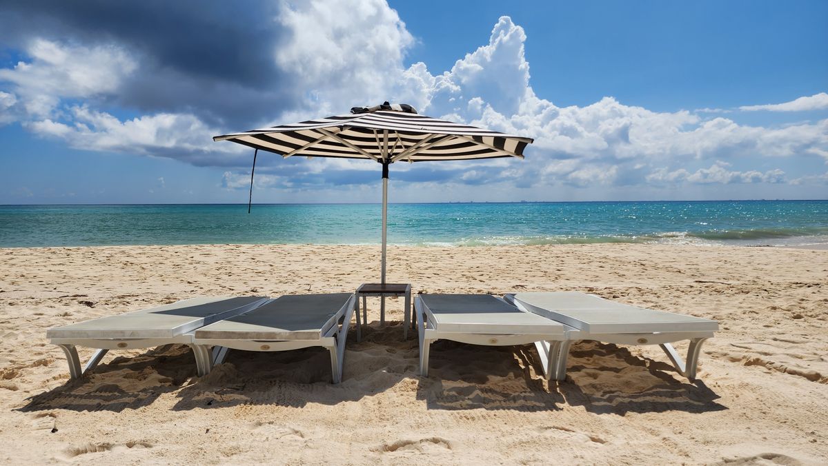 Serene Playa del Carmen beach with sunbeds and umbrella under a bright sky, perf