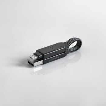 Minimalist photo of a sleek black USB flash drive with a braided loop against a white background.