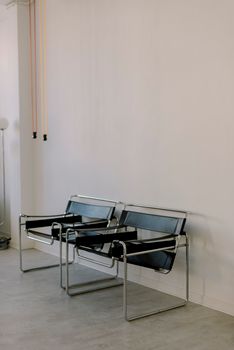 Two metal-framed chairs against a white wall in a minimalist room.