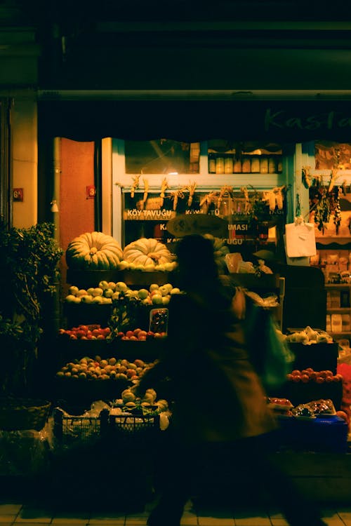 Person Walking near Market with Fruit and Vegetables at Night