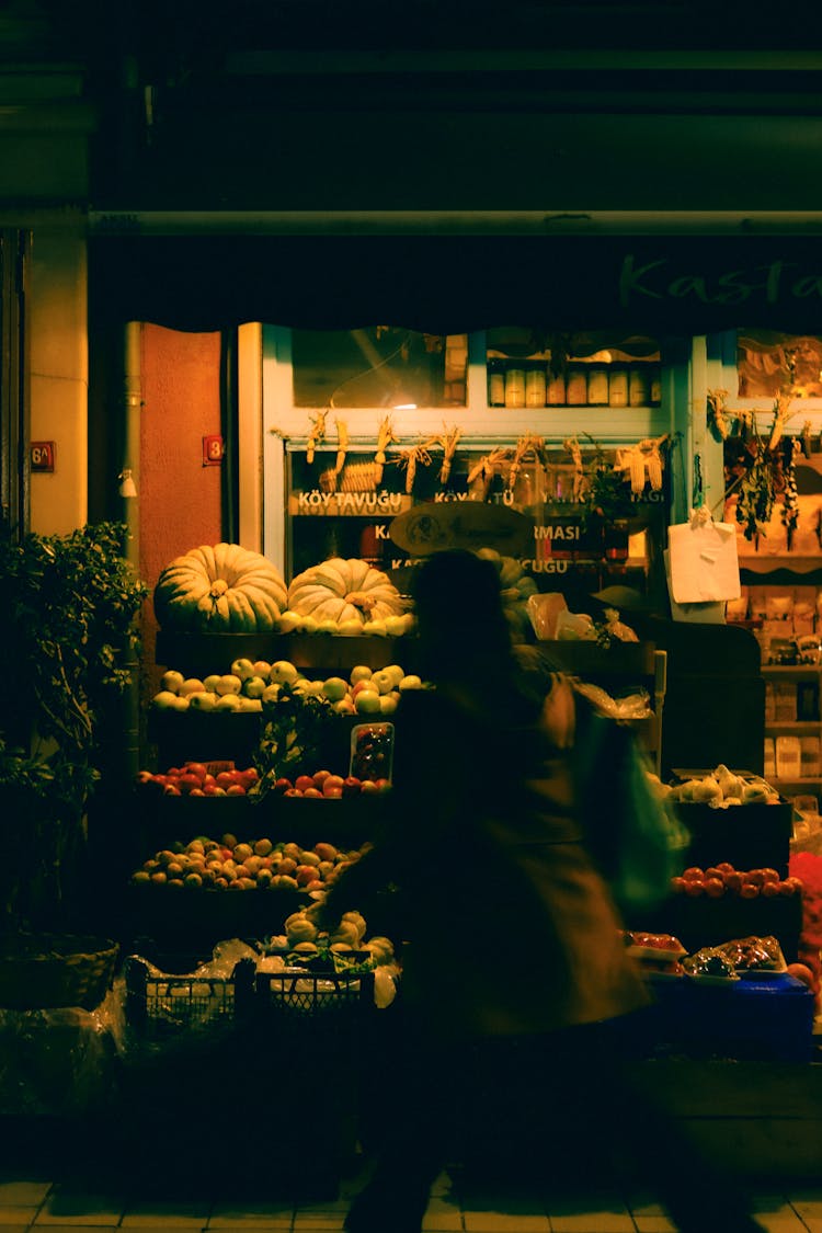 Person Walking Near Market With Fruit And Vegetables At Night