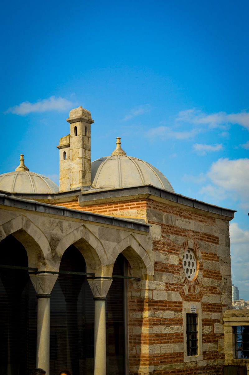 Ancient mosque architecture featuring stone arches and domes under a clear blue sky.