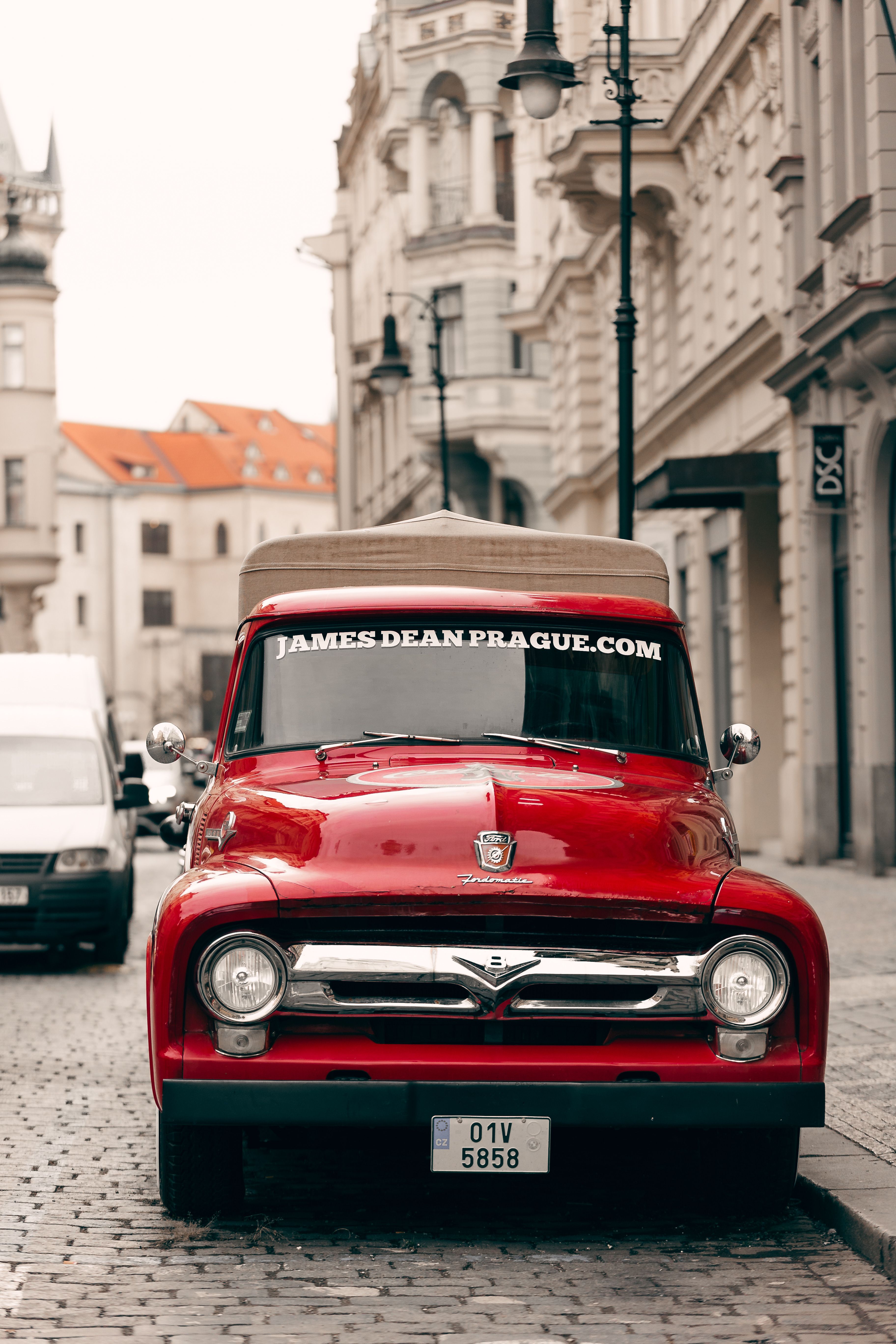 A charming vintage red truck parked on a cobblestone street in the heart of Prague's old town.
