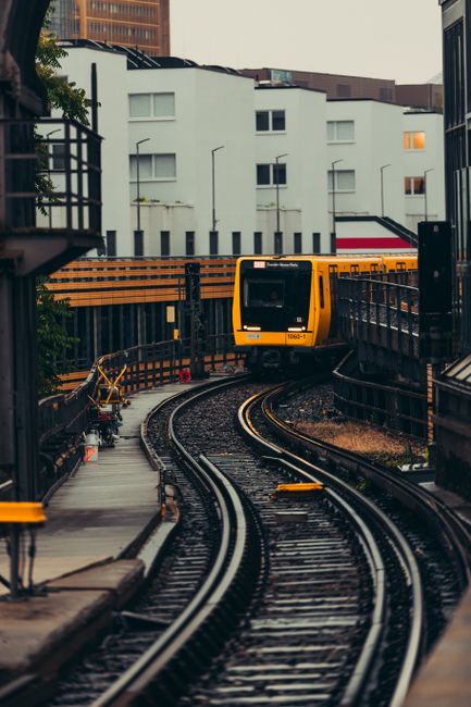 A metro train navigating curved tracks in an urban setting with residential buildings.
