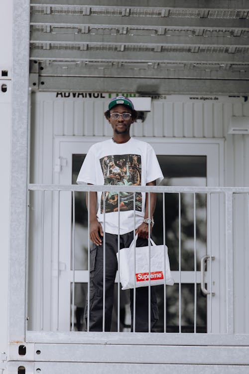 Man in Cap Standing with Bag Free Stock Photo