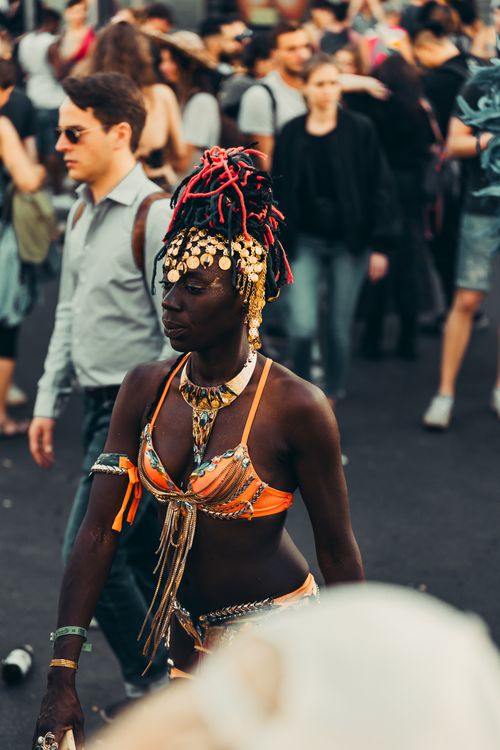 Free Woman in traditional clothing adorned with jewelry walking in a vibrant urban parade. Stock Photo