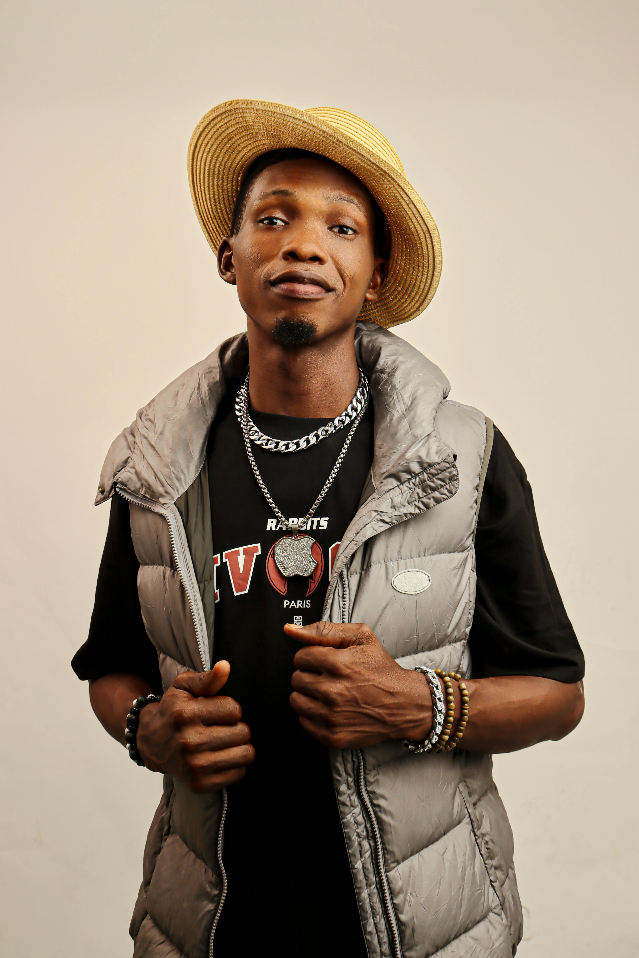 A fashionable man poses confidently, wearing a hat and stylish vest.