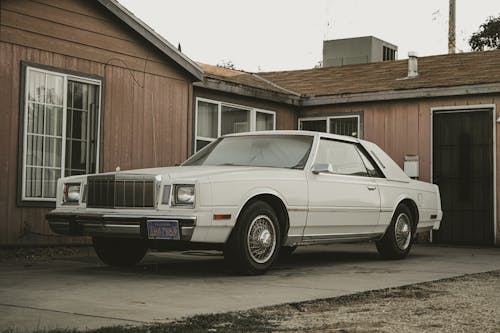 A Vintage White Chrysler Cordoba Parked in front of a Building 