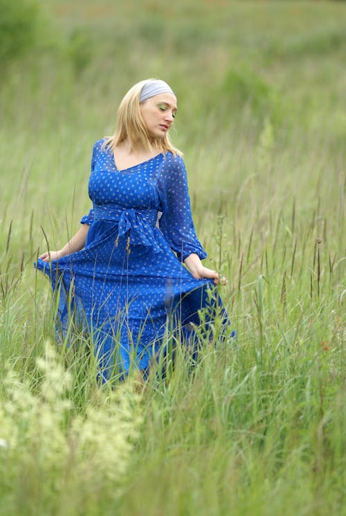 Young Woman in a Blue Dress Posing on a Meadow