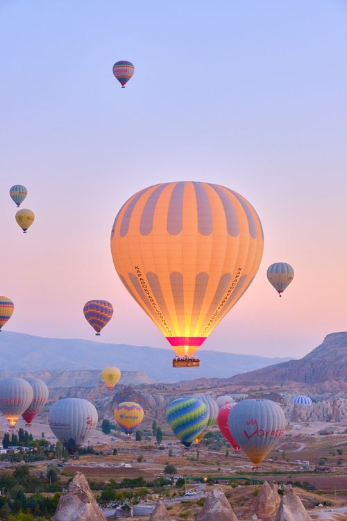 Free Majestic view of hot air balloons rising over Cappadocia's unique landscape at sunrise. Stock Photo