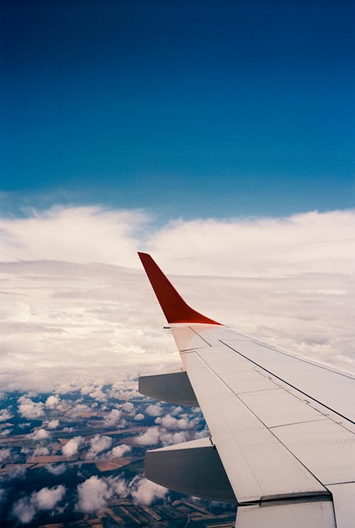 View of an Airplane Wing and Blue Sky with White Clouds 
