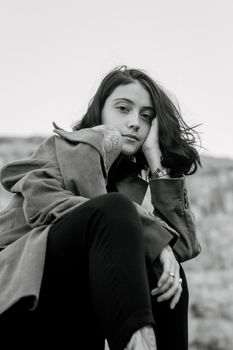 Stylish black and white outdoor portrait of a woman posing elegantly.