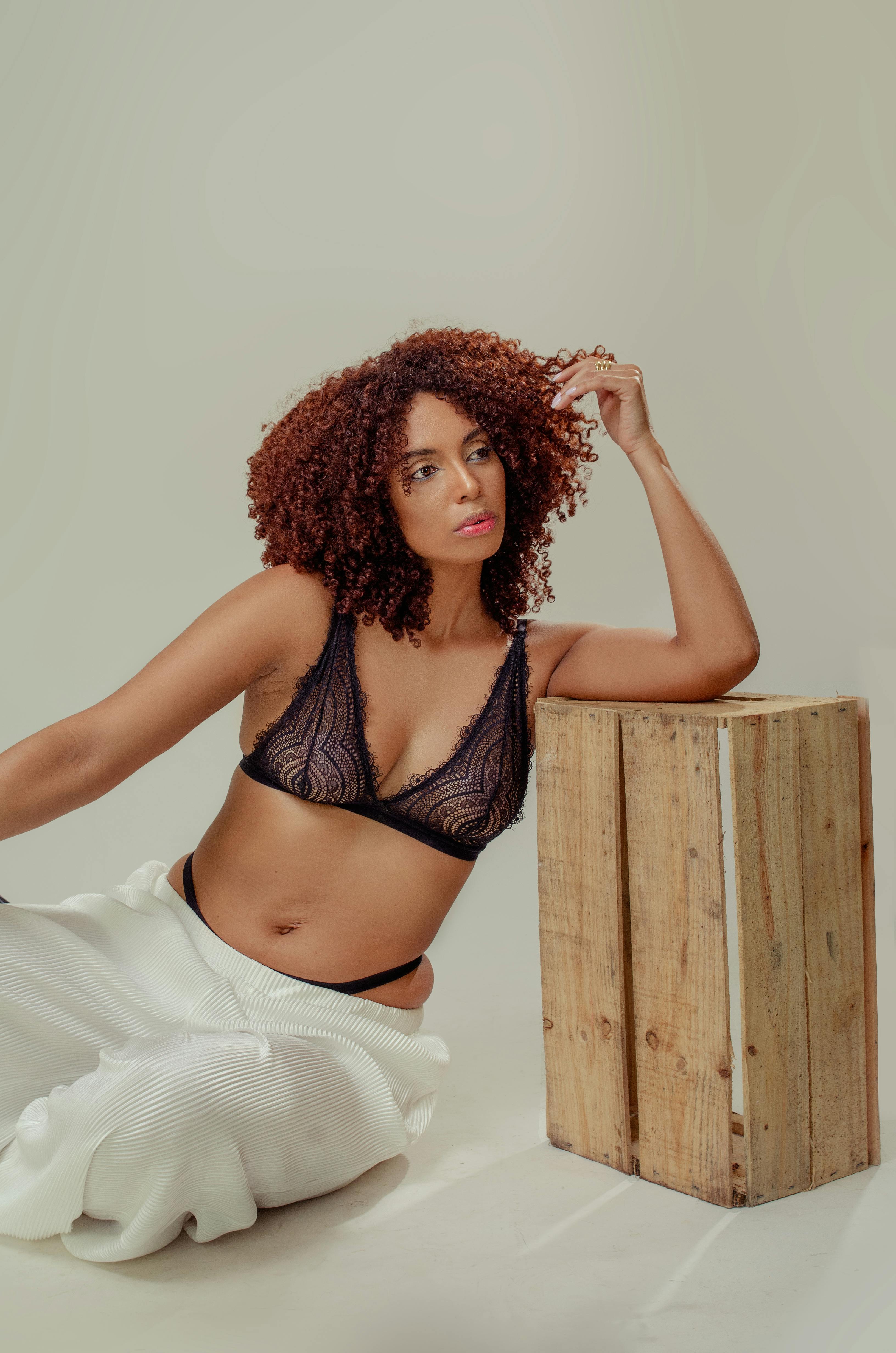 De franc Retrat de moda moderna d'una dona amb un top d'encaix negre i pantalons blancs asseguda amb gràcia Foto d'estoc