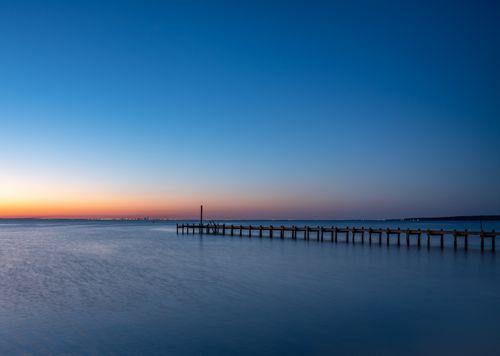 Free Peaceful seascape featuring a wooden pier at sunset, capturing tranquil ocean vibes. Stock Photo