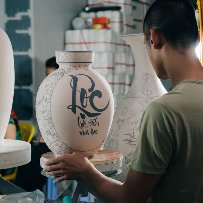 Artisan working on a handmade decorative vase in a workshop in Hanoi, Vietnam.