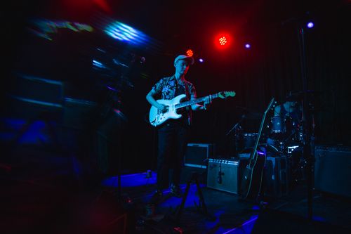Free Musician playing electric guitar on stage with vibrant lighting during a live performance. Stock Photo
