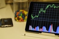 平板电脑显示股市数据，并配有智能手机和桌面上的彩色糖果